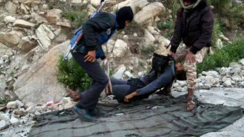 Fuerzas gubernamentales trasladan el cuerpo de un rebelde en Yemen.