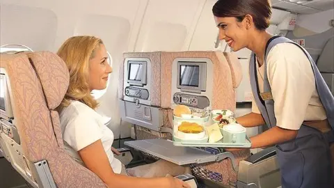 Servicio a una pasajera en un vuelo de Emirates Airline.