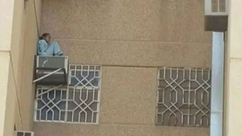 La empleada sentada en el aparato de aire acondicionado del sexto piso.