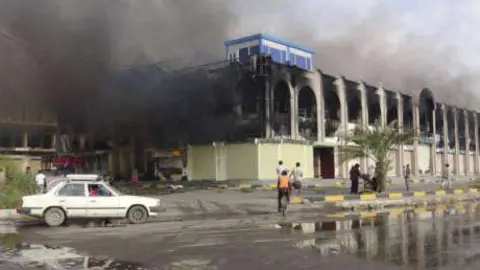 El humo se eleva desde un centro comercial después de los enfrentamientos en Adén.