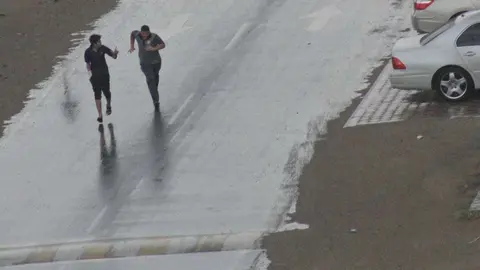 Dos jóvenes corren para ponerse a resguardo de la lluvia. (EL CORREO)