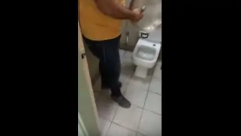 El trabajador friega un utensilio de la cocina en el baño.