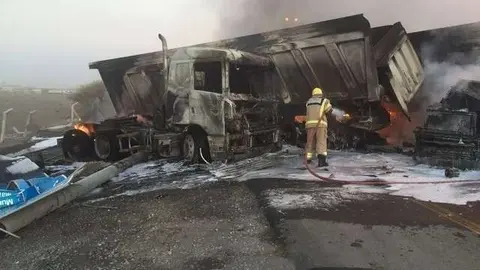 Un bombero apaga el fuego en los camiones siniestrados en Sharjah. (Policía de Sharjah)
