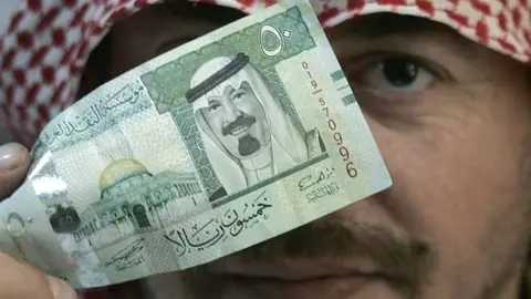 Un ciudadano saudí muestra un billete de curso legal en su país.