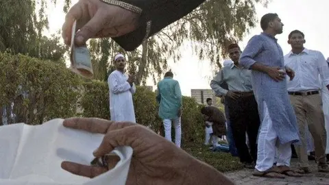 Un mendigo recibe una limosna en Dubai.