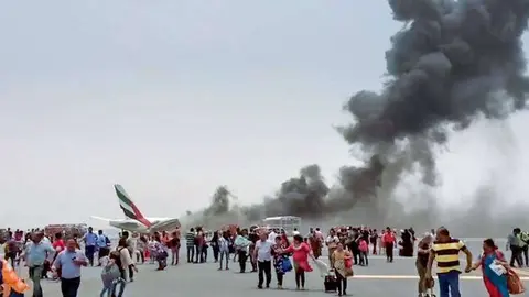 Pasajeros sobre la pista del aeropuerto de Dubai tras el desalojo del vuelo EK521.de Emirates.