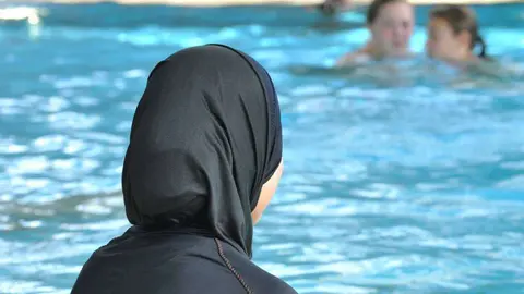 Una mujer en burkini en una piscina.