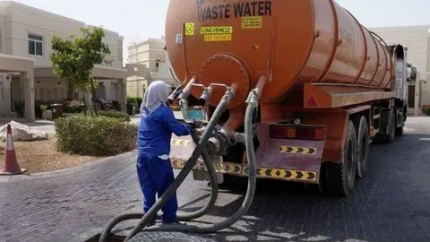 Un trabajador manipula un camión cisterna en una urbanización de EAU (The National).,