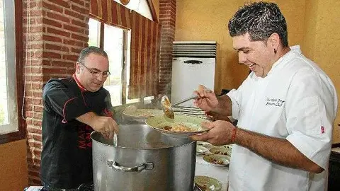 Mariano Andrés -izquierda- y José Vicente sirven la fabada en el Día de Asturias 