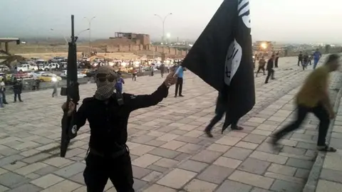 Un enmascarado con una bandera de Daesh.