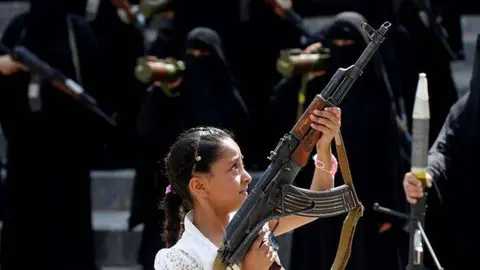 En la foto de Reuters se observa a mujeres y una niña portando armas pesadas.