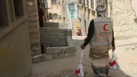 Un miembro de la Media Luna Roja reparte carne en Al Mukalla. (WAM)