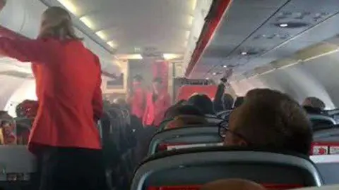 Las azafatas de Jetstar dan instrucciones a los pasajeros mientras la cabina se llena de humo. (Twitter)