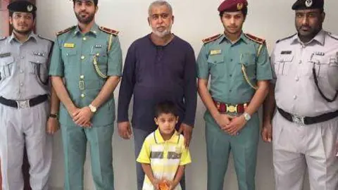 Una imagen del niño desaparecido junto a su padre y miembros de la policía.