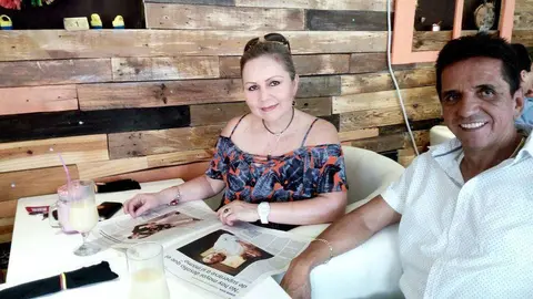 Los colombianos Cony y José Ramiro leen EL CORREO DEL GOLFO en el restaurante La Hacienda mientras aguardan que les sirvan la frijolada. (EL CORREO)