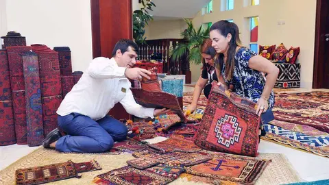 Invitadas a la exposición examinan el excelente trabajo llevado a cabo por las mujeres afganas en la confección de alfombras. (Manaf K. Abbas)
