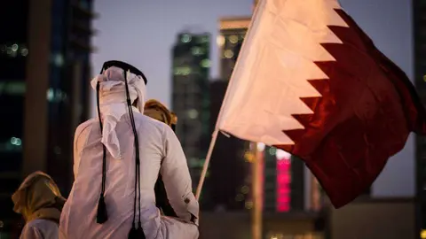 Un joven qatarí ante la bandera de su país.