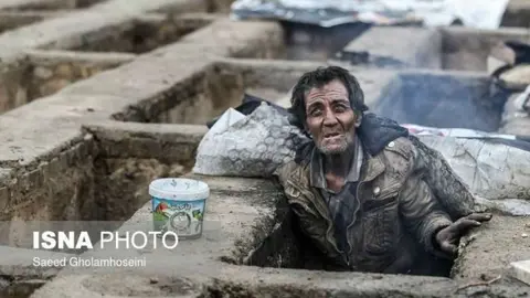 Un hombre sale de la tumba en la que se refugia del frío en un cementerio de Teherán. (@shahrvand_paper)