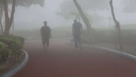 Residentes caminan entre la niebla por el paseo marítimo de la Corniche de Ras Al Khaimah. (R. Pérez)