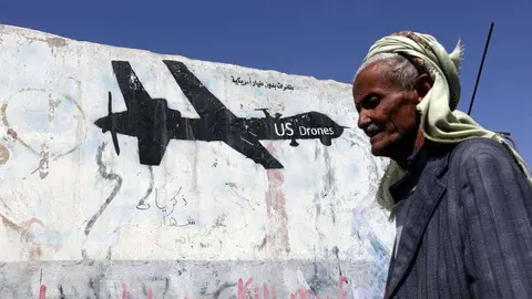 En la imagen de EFE un yemení camina frente a un grafiti de un dron de EEUU.