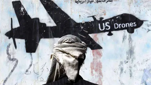 En la imagen de EFE, un joven mira un grafiti protesta en Saná.