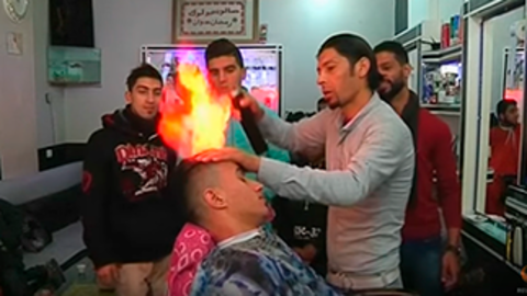 El barbero Ramadán Odwan aplica el tratamiento con fuego a uno de sus clientes.