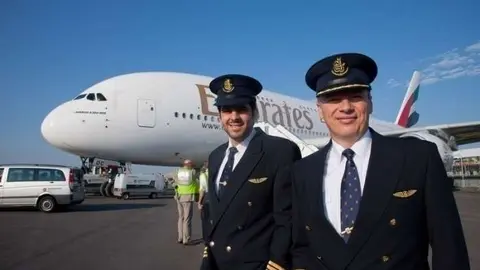 Personal de cabina ante un Emirates A380.