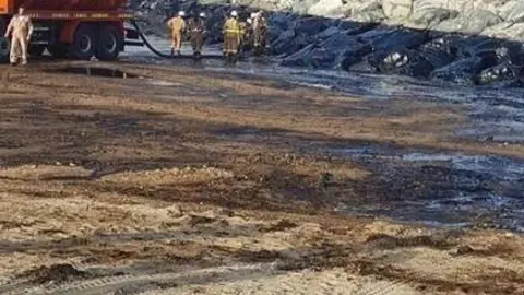 Trabajadores en Sharjah limpian la playa tras el vertido de petróleo.