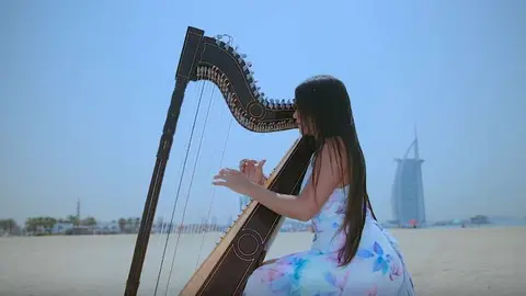 Luz Verón y su arpa en la playa del Burj Al Arab de Dubai.