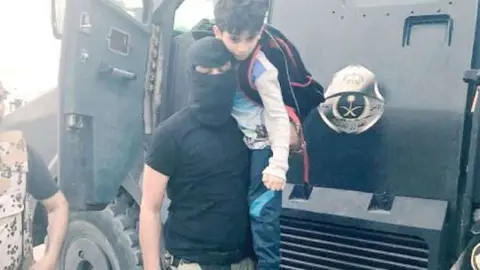 Un militar saudí ayuda a un chico de la zona de Al-Masourah. (Saudi Gazette)