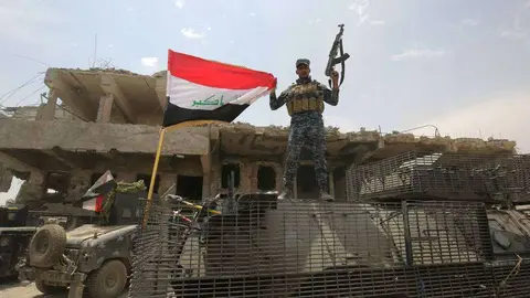 Un soldado iraquí iza una bandera en Mosul.
