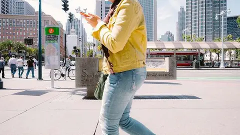 Una mujer camina por la calle usando su teléfono móvil. (Sonny Abesamis, Flickr)
