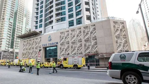 Operarios de limpieza trabajan para despejar los alrededores de la Torre Antorcha en Dubai Marina tras el incendio de este 4 de agosto. (Leslie Pableo,Khaleej Times)