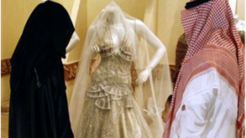 Una pareja saudí observa un traje de novia.