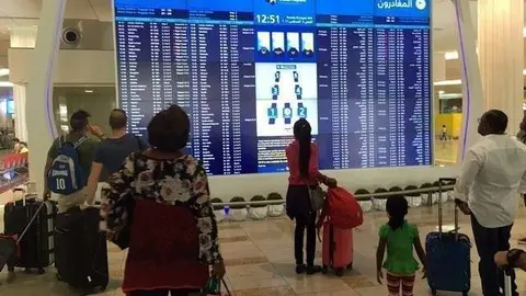 Viajeros miran la pantalla de salidas en el Aeropuerto Internacional de Dubai. (AFP)