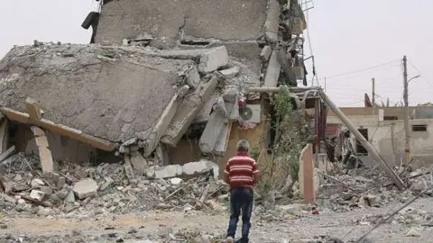 Una persona camina entre edificios destruidos y escombros en la ciudad de Tabqa, Raqqa, Siria. (UNICEF / Souleiman)