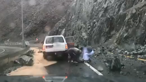 Varias personas retiran una roca desprendida sobre la carretera en Kalba Sweet Valley. (Ahmed al Badwawi, NCM)