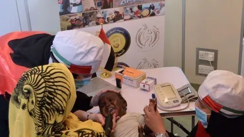 Voluntarios del programa de Sheikha Fatima en Sudán atienden a un niño. (WAM)