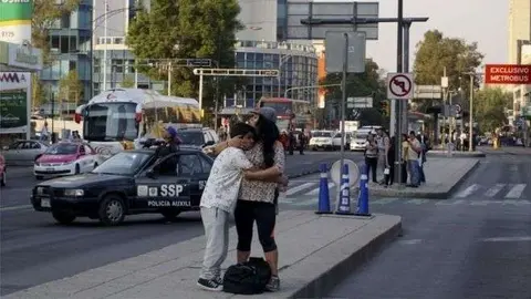 En la imagen de AFP, personas se abrazan en la calle, tras abandonar sus casas.