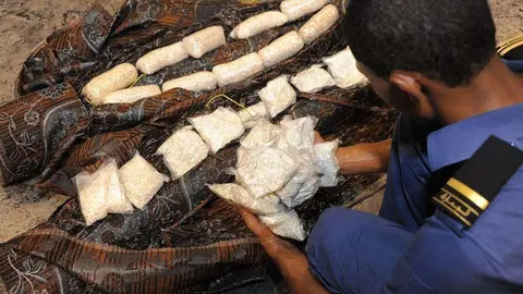 En la imagen de Aduanas de Dubai, un policía descubre píldoras prohibidas escondidas en una alfombra.