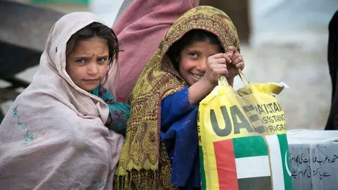 Una niña con un saco de ayuda alimentaria emiratí. (WAM)