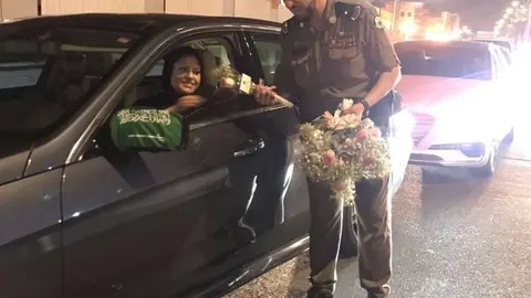 Un policía saudita entrega una rosa a una de las primeras mujeres conductoras tras el levantamiento de la prohibición. (@AboutHerOFCL)
