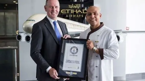 Tony Douglas, director ejecutivo de Etihad Aviation Group, y el chef Sanjay Thakur, muestran el reconocimiento. (WAM)