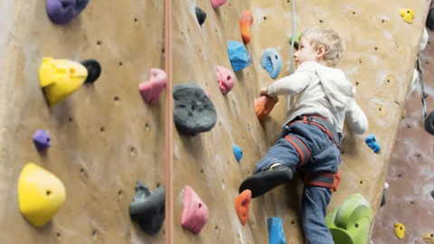 Niño escalando en rocódromo. 