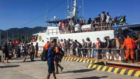 Los lugareños y turistas extranjeros  evacuados de las islas Gili desembarcanen el puerto de Bangsal, Lombok.