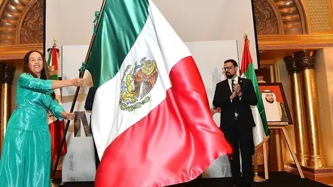La embajadora de México, Francisca Méndez, enarbola la bandera de México durante el Grito. (Manaf K. Abbas / EL CORREO)