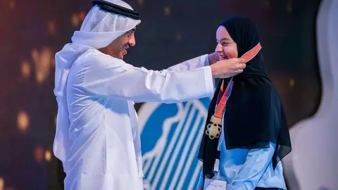El ministro Abdullah bin Zayed Al Nahyan coloca una medalla a una de las alumnas homenajeadas. (WAM)