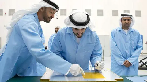 El jeque Hamdan bin Mohamed Al Maktoum, príncipe heredero de Dubai, firma la estructura del KhalifaSat durante una visita al Centro Espacial Mohammed bin Rashid, en presencia del jeque Mohamed bin Zayed Al Nahyan, príncipe heredero de Abu Dhabi. (WAM)