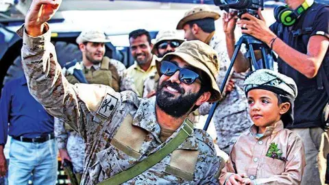 Un soldado saudí se fotografía con un niño yemení en Adén.