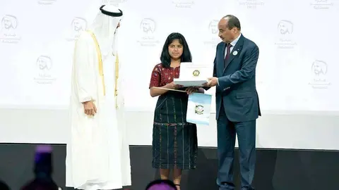 Momento en el que la representante de la escuela Impact de Guatemela, bandera de su país en mano, recibe en Abu Dhabi del jeque Mohammed bin Zayed Al Nahyan el Premio Zayed de Sostenibilidad en la categoría de las Américas. (WAM)